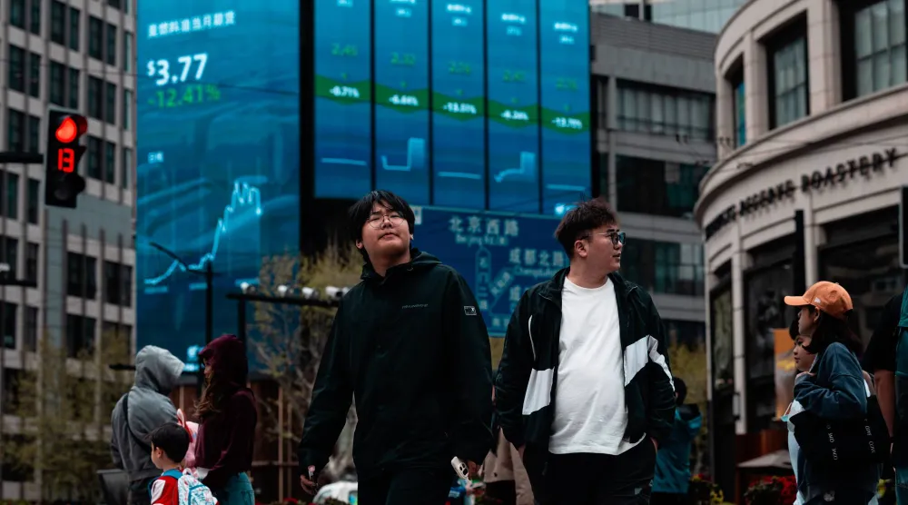 مشاة يمرون أمام شاشة عملاقة تعرض حركة الأسهم في مدينة شنغهاي الصينية (إ.ب.أ)