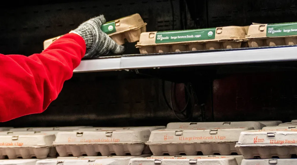 عامل يرتّب البيض على رف داخل سوبر ماركت في نيويورك (رويترز)