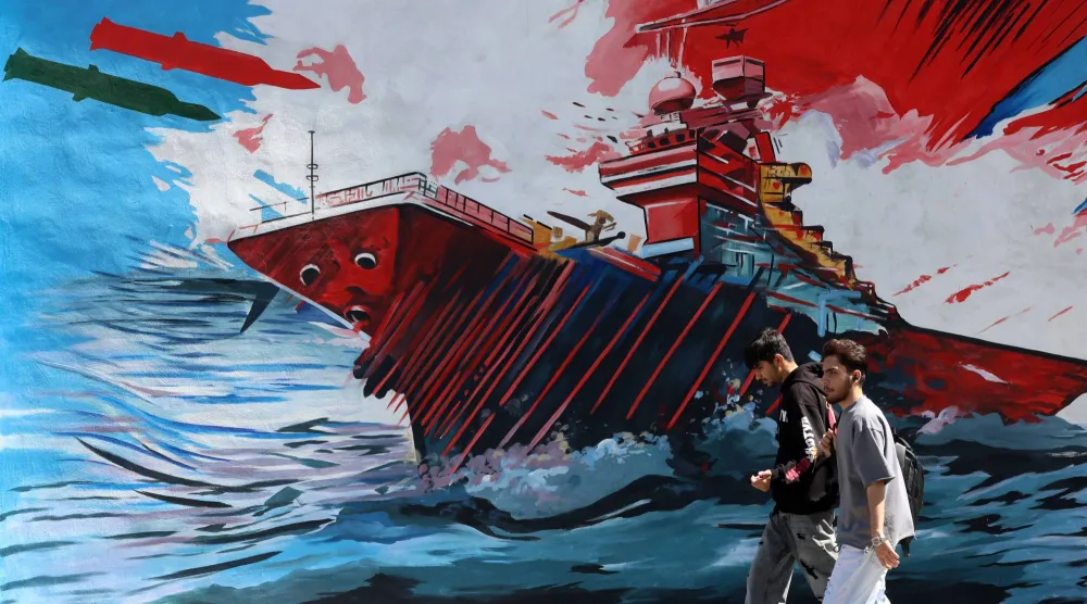 رجلان يمران أمام لوحة جدارية مناهضة للولايات المتحدة وإسرائيل في طهران (إ.ب.أ)