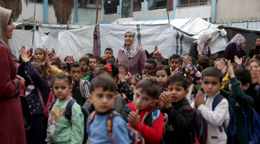 أطفال فلسطينيون من عائلات نازحة يتجمعون في ساحة مدرسة دير البلح المشتركة التابعة لوكالة «الأونروا» غرب دير البلح وسط قطاع غزة لتلقي بعض الدروس (أ.ف.ب)