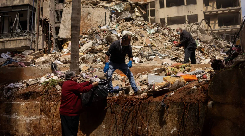 مواطنون يبحثون عن أغراضهم بين أنقاض مبنى تعرَّض لقصف إسرائيلي بمنطقة عين المريسة في بيروت (رويترز)