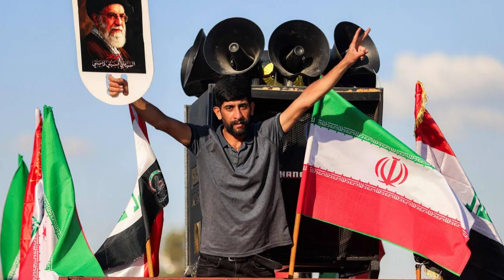 عراقي يلوّح بصورة للمرشد الإيراني علي خامنئي إلى جانب العلمين الإيراني والعراقي في ساحة التحرير وسط بغداد في 8 أبريل 2026 (أ.ف.ب)