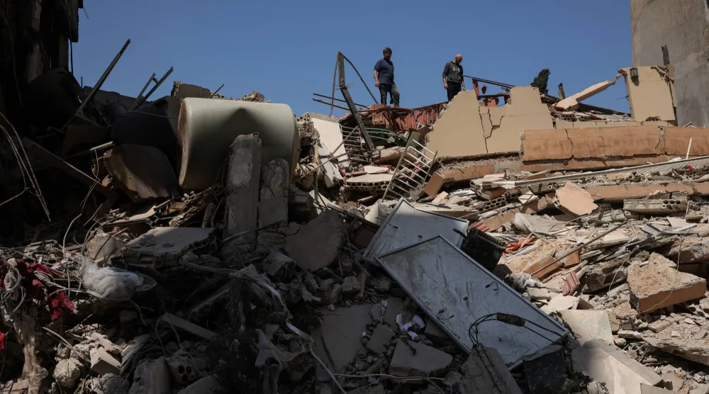 مواطنون يعاينون مبنى تم قصفه بغارة إسرائيلية في منطقة صور بجنوب لبنان (رويترز)