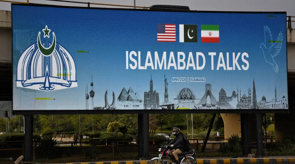 لوحة على جانب الطريق في إسلام آباد تشير إلى المحادثات الأميركية - الإيرانية (رويترز)
