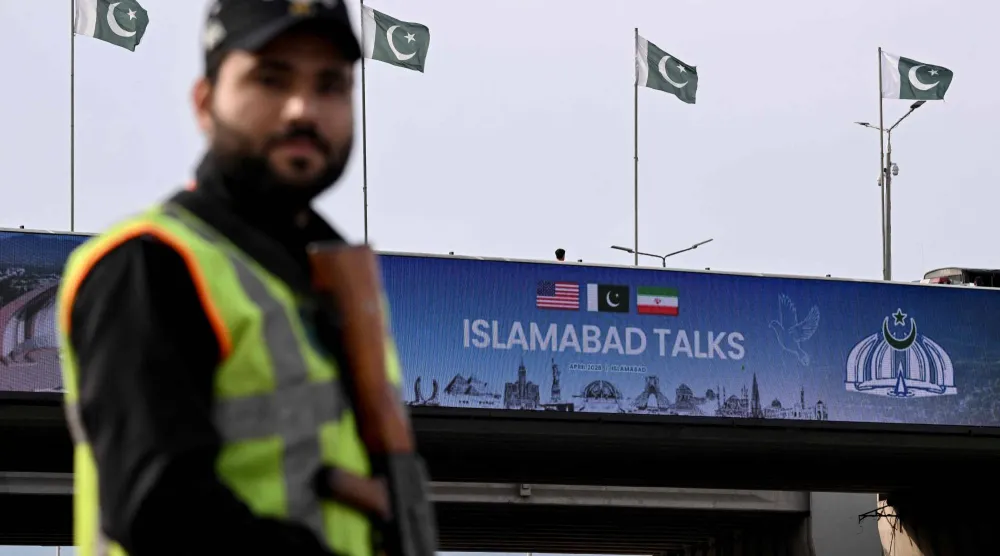 رجل شرطة باكستاني يقف أمام شاشة رقمية تعرض أخبار محادثات السلام الأميركية الإيرانية على أحد الطرق في إسلام آباد (أ.ف.ب)