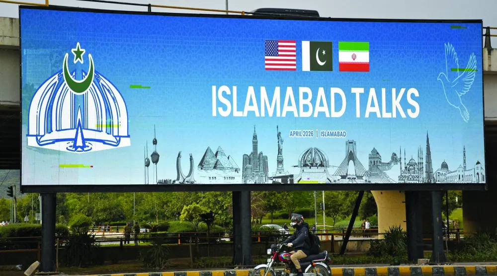A man rides his motorbike past a billboard installed alongside a road as Pakistan prepares to host the US and Iran for peace talks, in Islamabad, Pakistan, April 10, 2026. REUTERS/Waseem Khan 