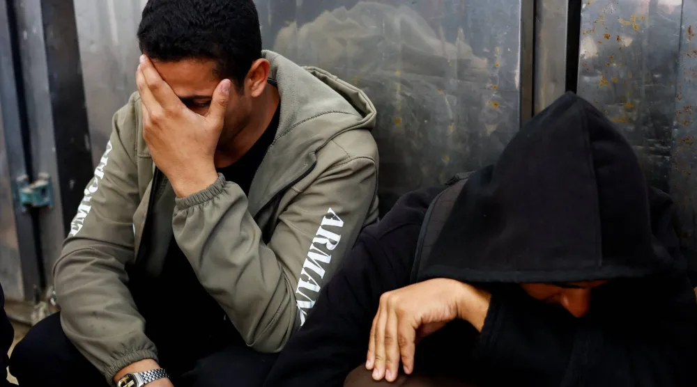 فلسطينيان متأثران خلال تشييع قتلى سقطوا بغارة إسرائيلية في دير البلح وسط قطاع غزة السبت (د.ب.أ)