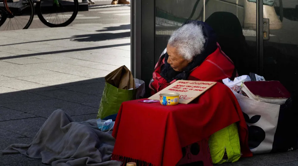 امرأة بلا مأوى تجلس في أحد شوارع باريس (أ.ف.ب)