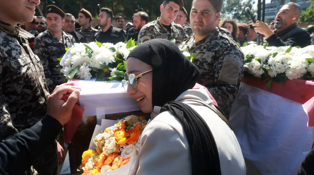لبنانية وعناصر في أمن الدولة يبكون 13 عسكرياً قُتلوا في استهداف إسرائيلي لمقر «أمن الدولة» في النبطية وشُيّعوا في مراسم عسكرية السبت (رويترز)