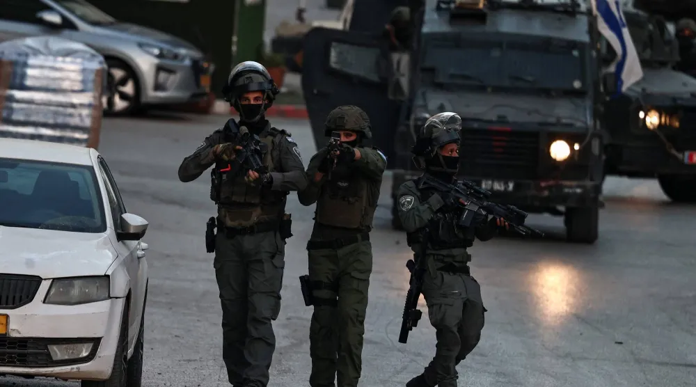 جنود إسرائيليون يمشطون أحد شوارع بلدة كفر عقب في الضفة الغربية (أ.ف.ب)