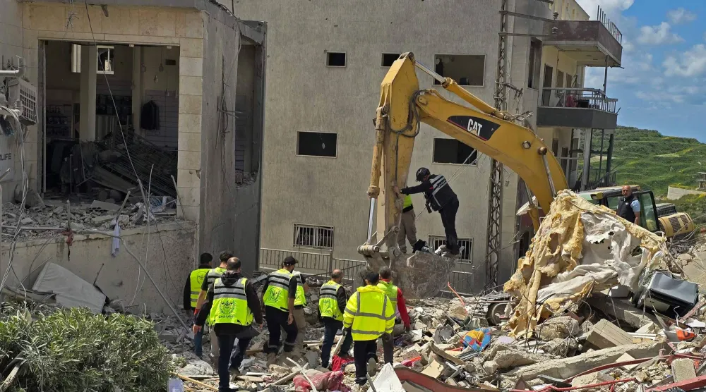 عناصر الدفاع المدني يبحثون عن القتلى والجرحى تحت أنقاض مبنى استهدف في بلدة قانا في جنوب لبنان ما أدى إلى سقوط قتلى وجرحى (أ.ف.ب)