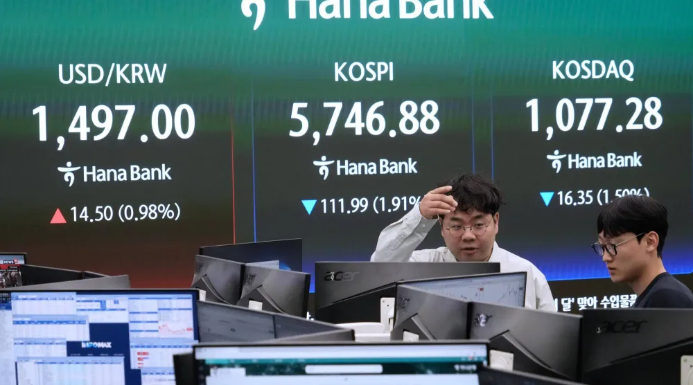 يعمل متداولو العملات بالقرب من شاشة تعرض مؤشر «كوسبي» الكوري (أ.ب)