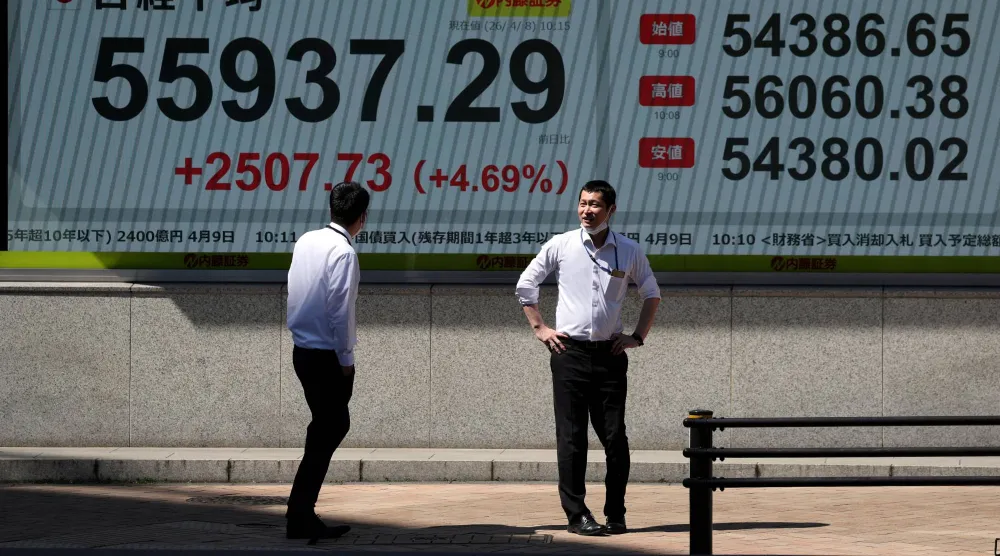 مشاة يمرُّون أمام شاشة تعرض حركة الأسهم في العاصمة اليابانية طوكيو (رويترز)