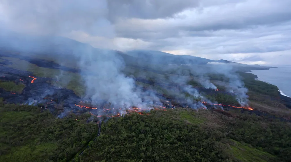 An aerial picture shows smoke rising as lava from the Piton de la Fournaise volcano  comes to a halt in Saint-Philippe, on the French Indian ocean island of Reunion, on April 2, 2026. (Photo by Richard BOUHET / AFP)