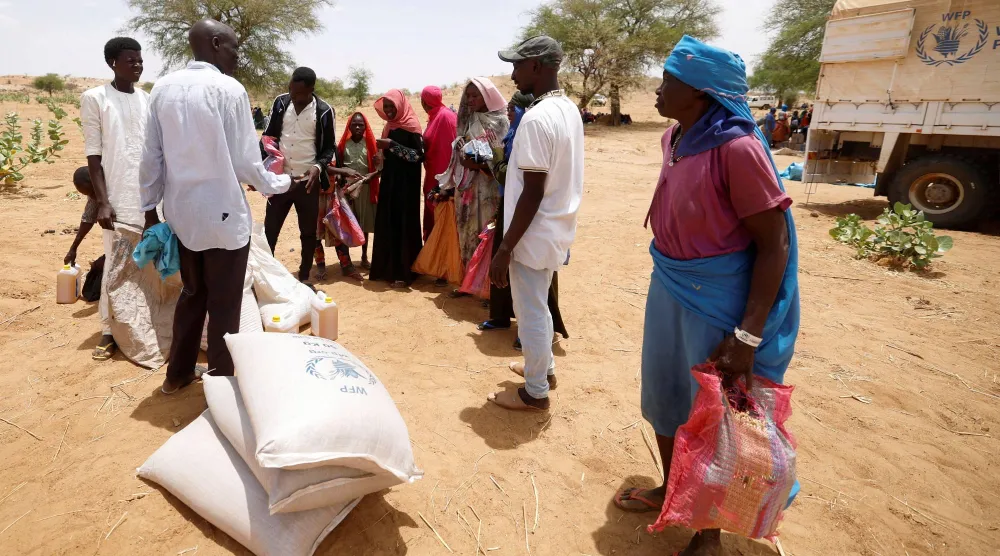 نازحون سودانيون في تشاد ينتظرون لتقاسم حصص من مواد غذائية وزّعها برنامج الأغذية العالمي يوم 9 مايو 2023 (رويترز)