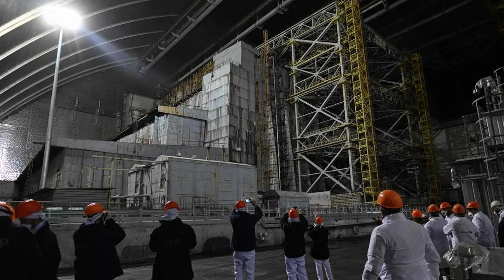 Representatives of Greenpeace and media stand in front of the sarcophagus covering the destroyed fourth reactor under the New Safe Confinement (NSC), at the Chernobyl Nuclear Power Plant on April 9, 2026. (AFP)