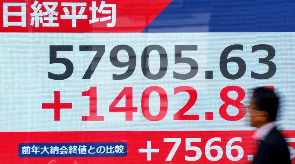 رجل يمر أمام شاشة تعرض حركة الأسهم في وسط العاصمة اليابانية طوكيو (أ.ف.ب)