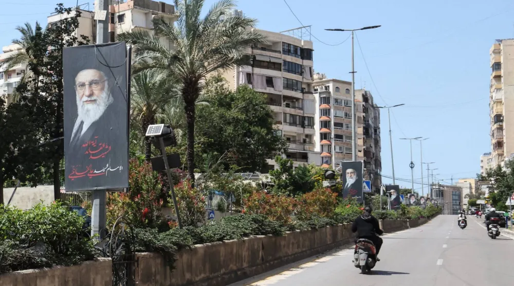 دراجات نارية تمرّ أمام ملصقات تُظهر المرشد الإيراني السابق علي خامنئي في الضاحية الجنوبية لبيروت (أ.ف.ب)