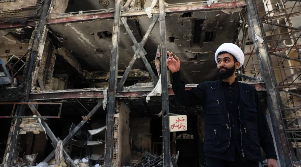 رجل دين إيراني يتحدث إلى وسائل الإعلام أمام مبنى سكني تعرض لغارات جوية أميركية - إسرائيلية قبل أيام من دخول وقف إطلاق النار لمدة أسبوعين بين إيران والولايات المتحدة حيز التنفيذ... اليوم في طهران (أ.ف.ب)