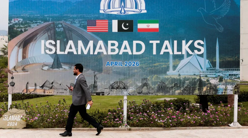 رجل يمر بجوار لوحة إعلانية بالقرب من المركز الإعلامي حيث عقدت الجولة الأولى من المحادثات بين الولايات المتحدة وإيران في إسلام آباد الأسبوع الماضي (رويترز)