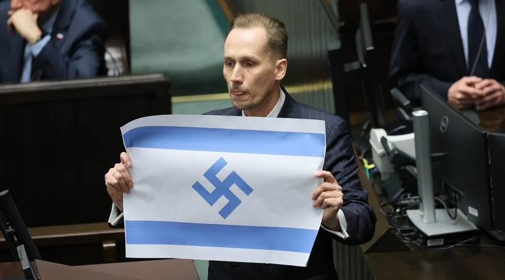 Polish Far-right Confederation party MP Konrad Berkowicz dsiplays an Israeli flag marked with a swastika in the Sejm in Warsaw, Poland, 14 April 2026. (EPA)