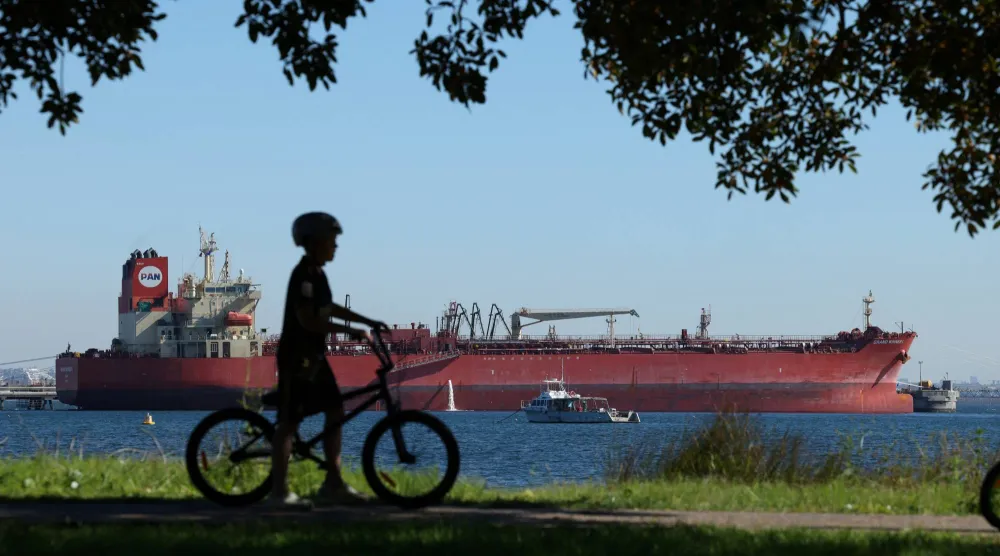 طفل يدفع دراجة هوائية بالقرب من ناقلة نفط ومواد كيميائية في كورنيل بمدينة سيدني، أستراليا (رويترز)