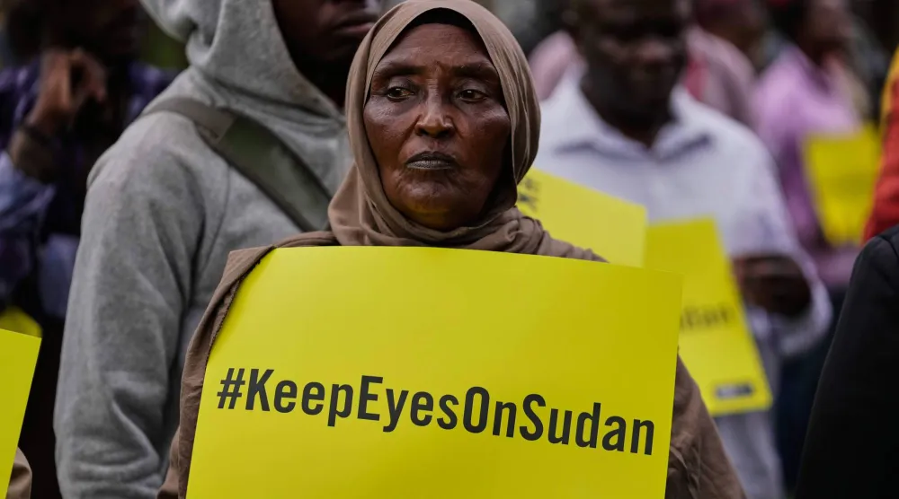 سيدة ترفع لافتة خلال فعالية في نيروبي بكينيا بمناسبة دخول الحرب بالسودان عامها الرابع يوم الأربعاء (أ.ب)