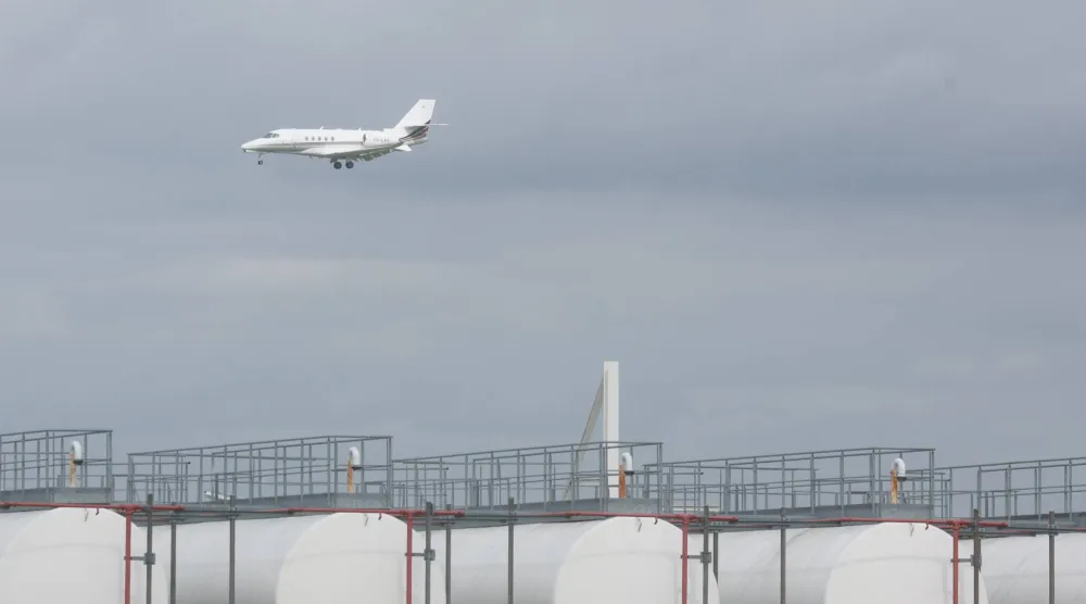 طائرة تمر خلف منشآت تخزين الكيروسين بمطار لييغ في بلجيكا (إ.ب.أ)