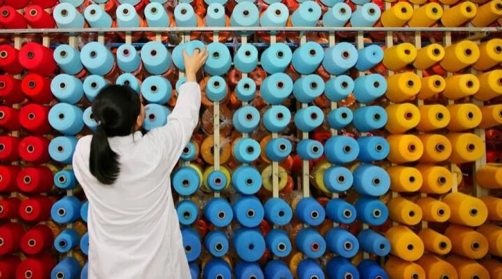 موظفة ترتّب بكرات الخيوط في مصنع نسيج في هايان بمقاطعة جيانغسو - الصين (رويترز)