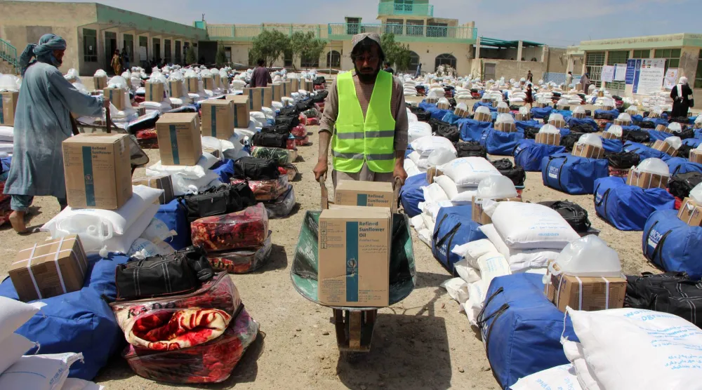 أناس متأثرون بالفيضانات يتلقون مساعدات في قندهار بأفغانستان (إ.ب.أ)