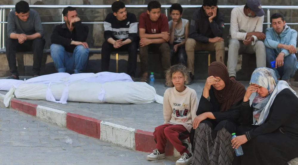 فلسطينيون إلى جوار جثماني الشقيقين عبد الملك وعبد الستار العطار اللذين قُتلا في غارة إسرائيلية قبل تشييعهما في مدينة غزة يوم الخميس (رويترز)