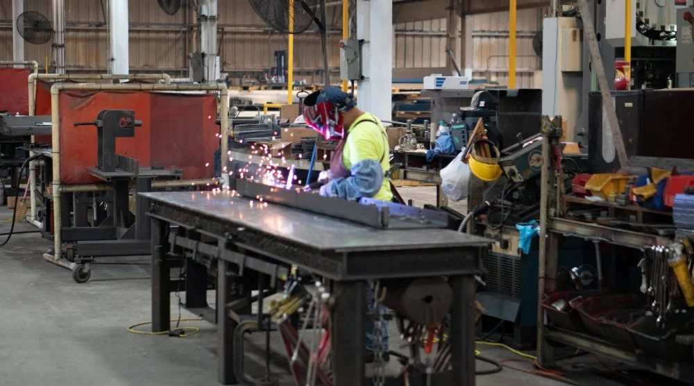 يقوم عامل بلحام الجزء السفلي من لوح تسوية لآلة رصف الطرق داخل مصنع كالدير براذرز في ولاية كارولينا الجنوبية (رويترز)