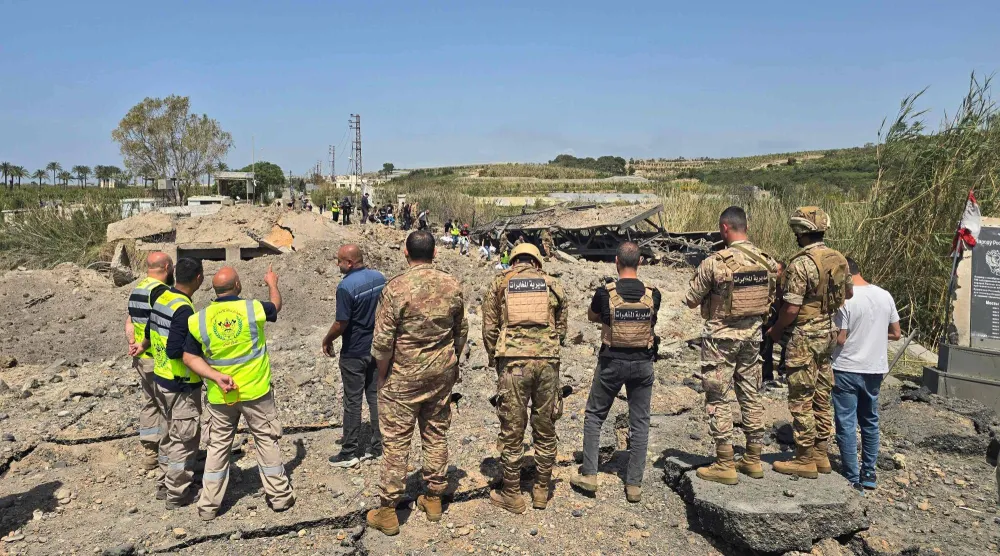جنود الجيش اللبناني وعناصر الدفاع المدني يتفقدون موقع الغارات الإسرائيلية التي استهدفت جسر القاسمية المبني فوق نهر الليطاني في منطقة القاسمية جنوب لبنان (أ.ف.ب)