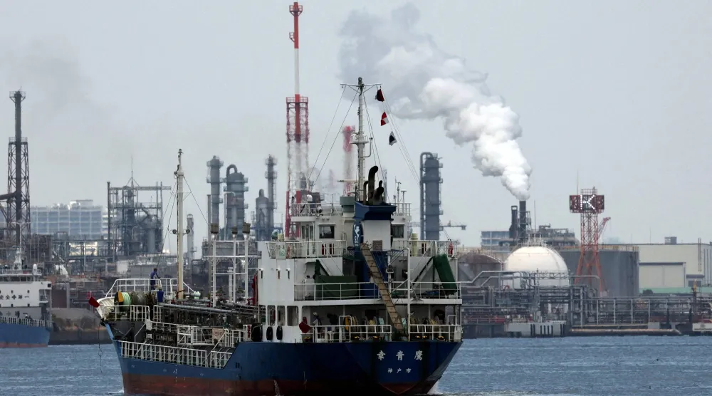 سفينة تبحر قبالة مصفاة نفطية في المنطقة الصناعية بمدينة كاوازاكي اليابانية جنوب العاصمة طوكيو (رويترز)