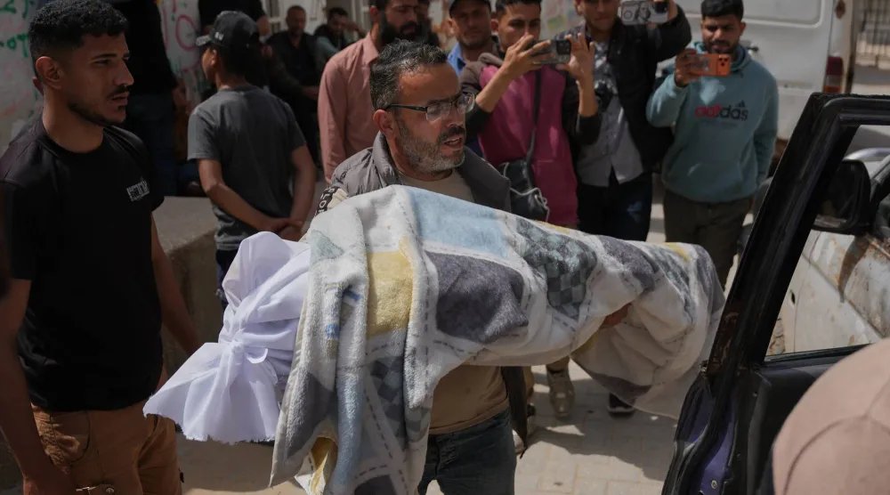 فلسطيني يحمل جثمان فتى (12 عاماً) قُتل برصاص إسرائيلي خلال تشييعه خارج «مستشفى الشفاء» بمدينة غزة الجمعة (أ.ب)