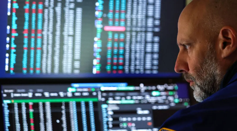 متداول يراقب شاشات تعرض مؤشرات الأسهم في بورصة نيويورك (أ.ف.ب)