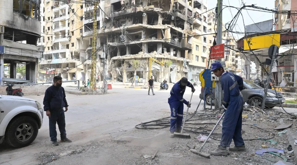 عمال ينظفون شوارع الضاحية الجنوبية لبيروت من الركام تمهيداً لعودة السكان (الشرق الأوسط)