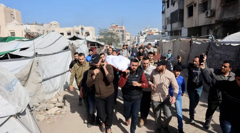 Filistinliler, İsrail'in Gazze şehrine düzenlediği baskında öldürülen bir kişinin cesedini taşıyor (AFP)
