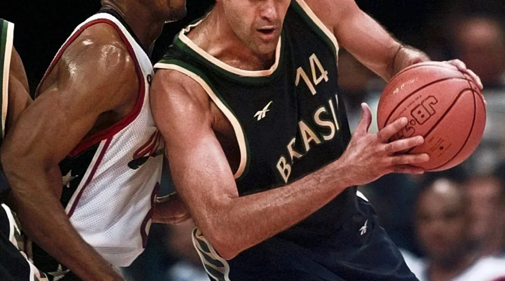 البرازيلي أوسكار شميدت (14) يتجاوز سكوتي بيبن (8) لاعب الولايات المتحدة في دورة الألعاب الأولمبية الصيفية المئوية في أتلانتا عام 1996 (أ.ب)