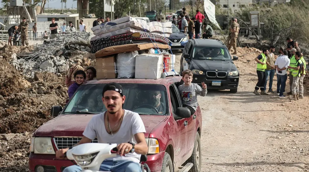  Güney Lübnan'dan yerinden edilmiş insanlar, Litani Nehri'nin güneyine ulaşmak için yıkılmış bir köprüden geçiyor (Reuters)