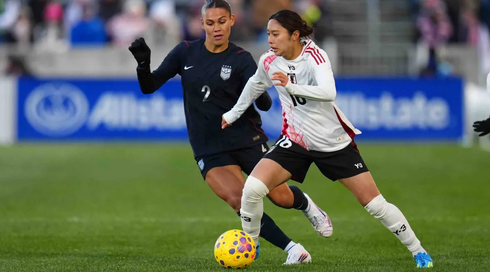 لاعبة وسط منتخب اليابان يوزوكي ياماموتو تسيطرعلى الكرة أمام مهاجمة منتخب الولايات المتحدة ترينيتي رودمان (أ.ب)