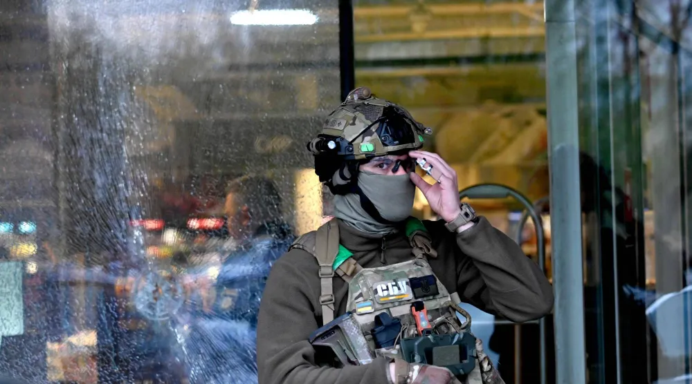 عنصر من القوات الخاصة التابعة للشرطة أمام فتحة أحدثها رصاصة في سوبرماركت عقب إطلاق النار في كييف اليوم (أ.ف.ب)