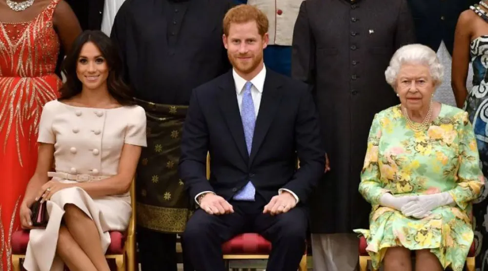 الأمير هاري وزوجته ميغان ماركل مع جدته الراحلة الملكة إليزابيث (رويترز)