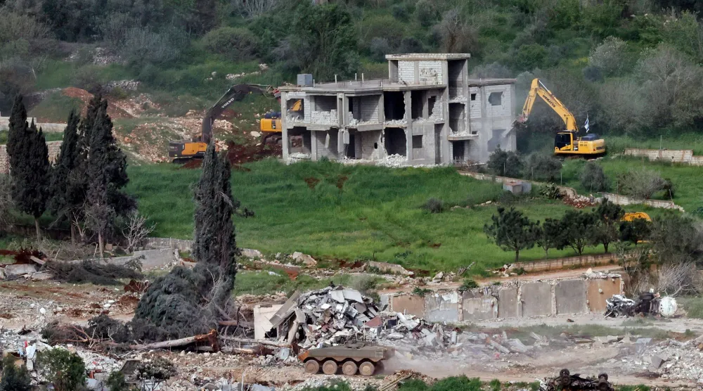 دبابات إسرائيلية في ميس الجبل وتظهر في الصورة جرافات تهدم ما تبقى من منازل في القرية الحدودية بجنوب لبنان (أ.ف.ب)