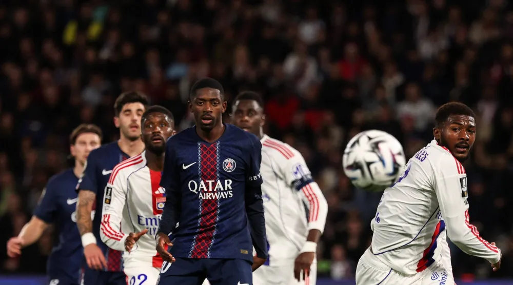 مهاجم باريس سان جيرمان عثمان ديمبيلي ومدافع أولمبيك ليون أينسلي ميتلاند نايلز يتابعان الكرة (أ.ف.ب)