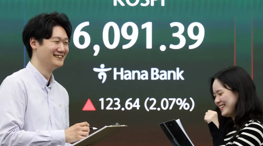 يعمل متداولون كوريون جنوبيون أمام شاشة بيانات مالية تُظهر ارتفاع مؤشر «كوسبي» ببنك هانا في سيول (إ.ب.أ)