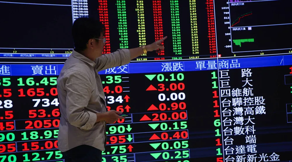 رجل يتابع شاشة تعرض مؤشرات مالية داخل بورصة تايوان في تايبيه (إ.ب.أ)