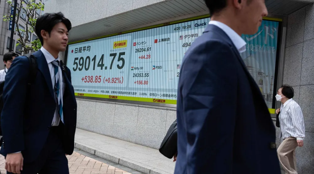 مشاة يمرون أمام شاشة تعرض حركة الأسهم في وسط طوكيو (أ.ف.ب)