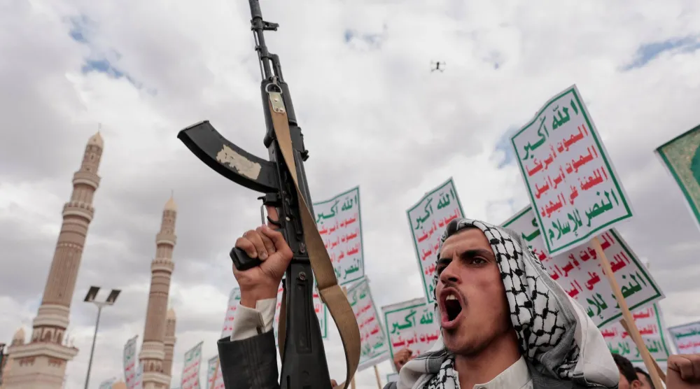 عنصر حوثي يرفع بندقية خلال حشد في صنعاء للتضامن مع إيران و«حزب الله» اللبناني (رويترز)
