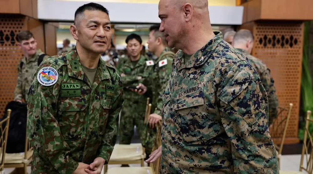 ضباط من اليابان والولايات المتحدة يتحدثون مع بعضهم خلال حفل افتتاح مناورات «باليكاتان» (كتفاً في كتف) الفلبينية الأميركية التي أقيمت بمانيلا (إ.ب.أ)